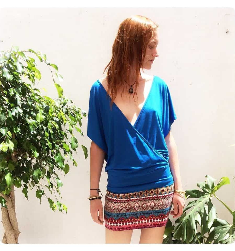 japamala customer in the store's inner courtyard, surrounded by plants and natural light. Wearing the versatile summer top in blue 