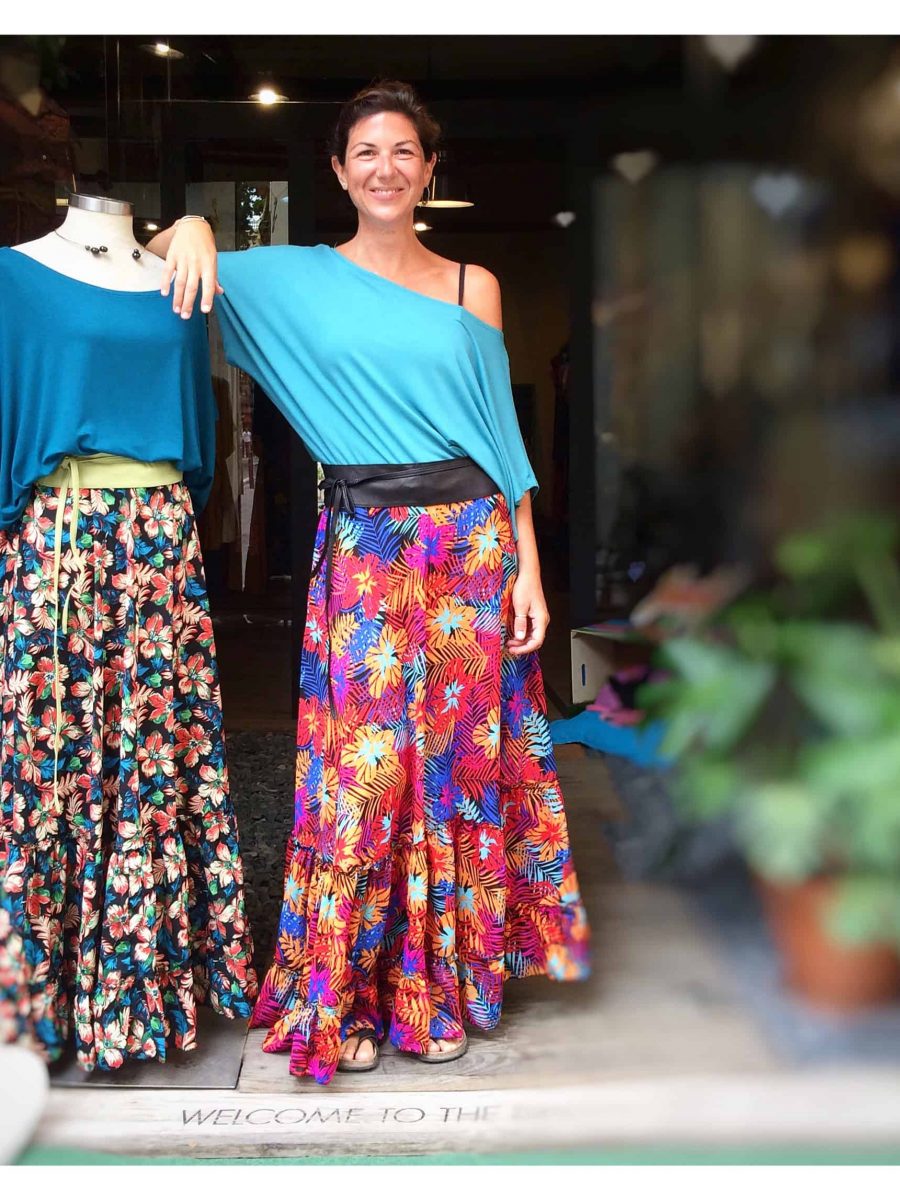 customer with the summer bat top in blue, combined with a maxi skirt printed with original design. The customer is at the entrance of the store in gracia. 