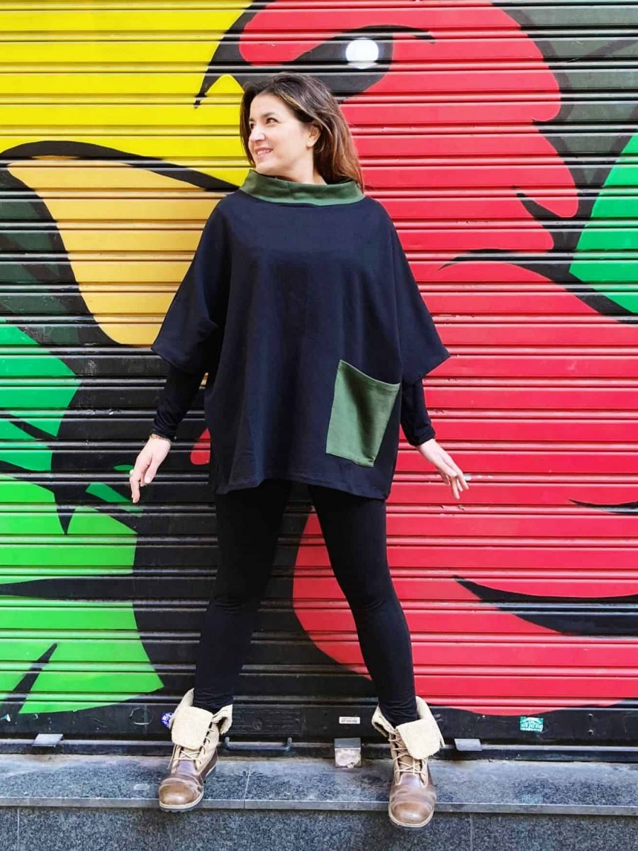 customer with the cotton poncho tunic in front of a colorful mural of the streets of gracia, in barcelona.
