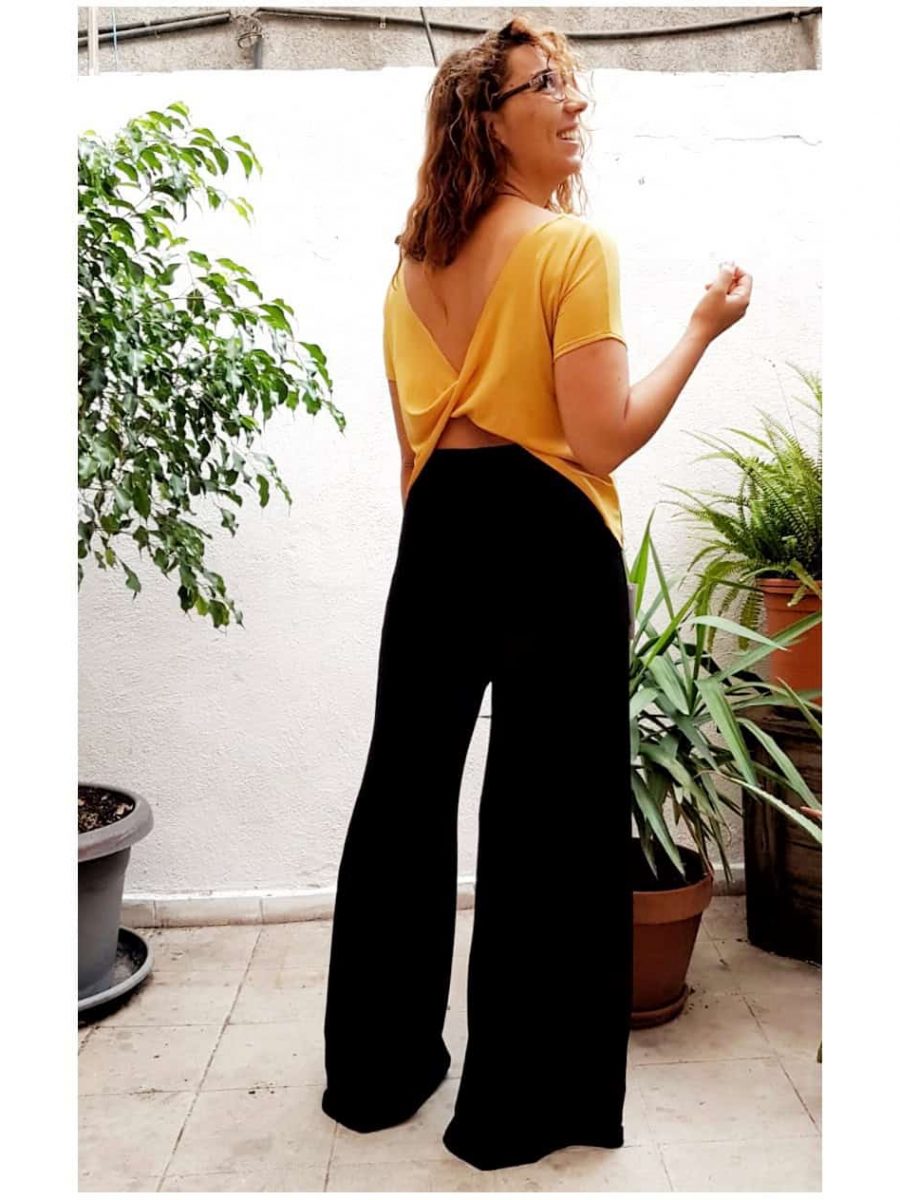 stylish customer in the inner courtyard of japamala, our store in gracia, wearing the yellow sleeveless crossover top and the long double wide trousers in black.
