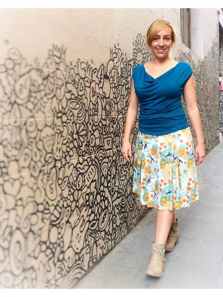 customer wearing the blue sleeveless reversible top outside the store, in the streets of the iconic graica neighborhood in barcelona. she wears the top in its open neck version. 