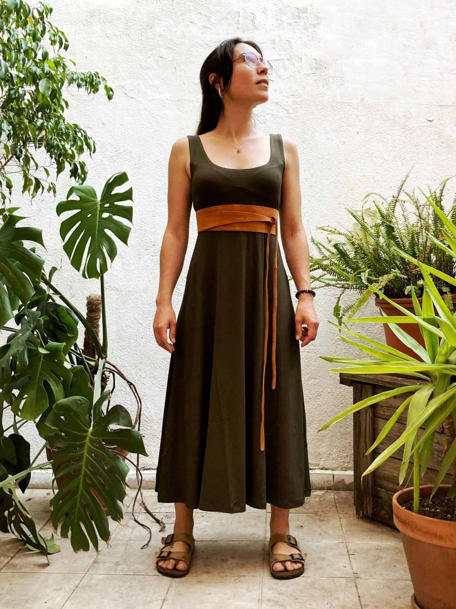 clienta al pati interior de la botiga a barcelona lluint l'iconic vestit ballarina midi sense mànigues. envoltada de plantes i llum natural 