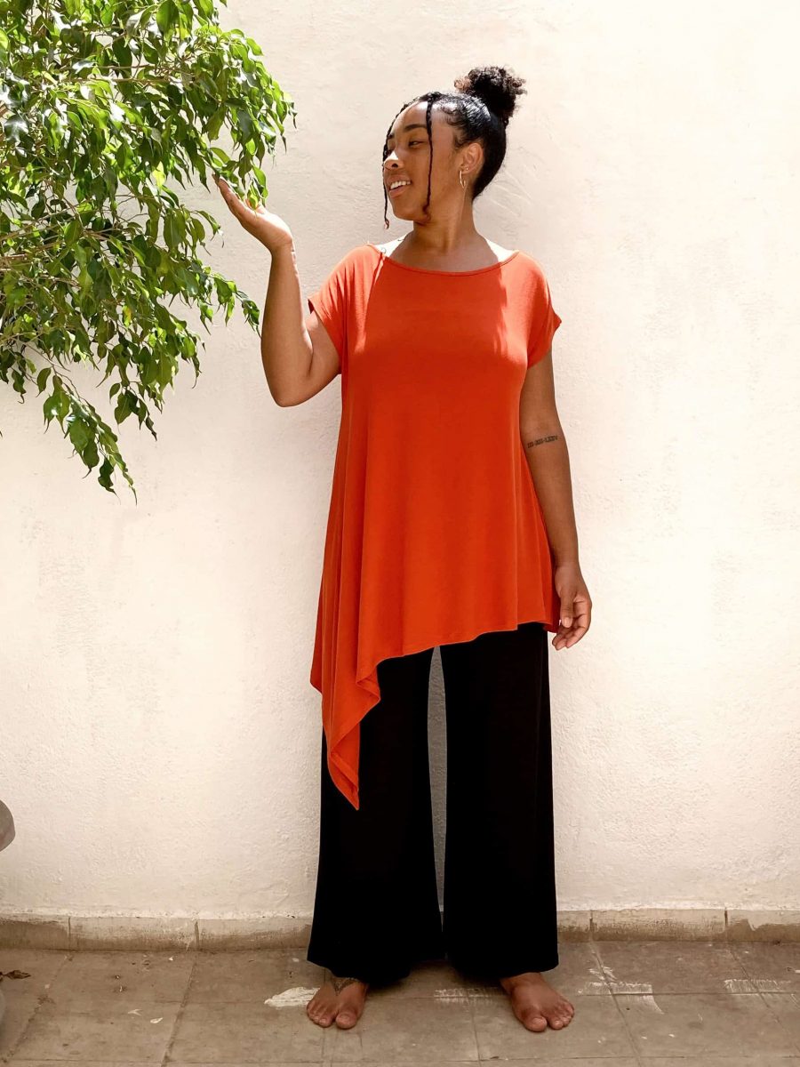 customer wearing her orange boat tunic with black japamala trousers inside the store with natural light and plants