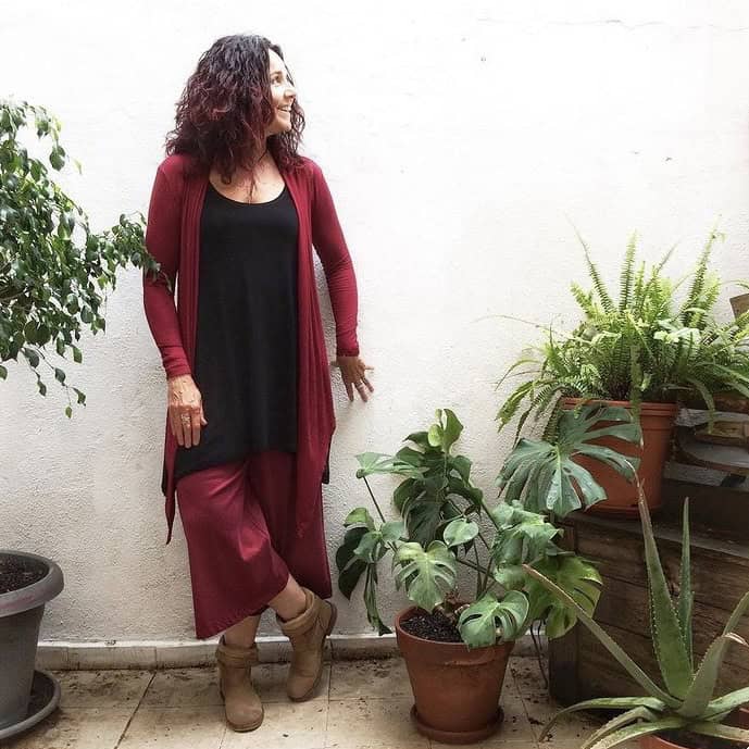 la nostra clienta feliç al pati de la botiga a barcelona, lluint una torera fina vermella, una camisa tunica negra i un pantaló cropped vermell fluid.