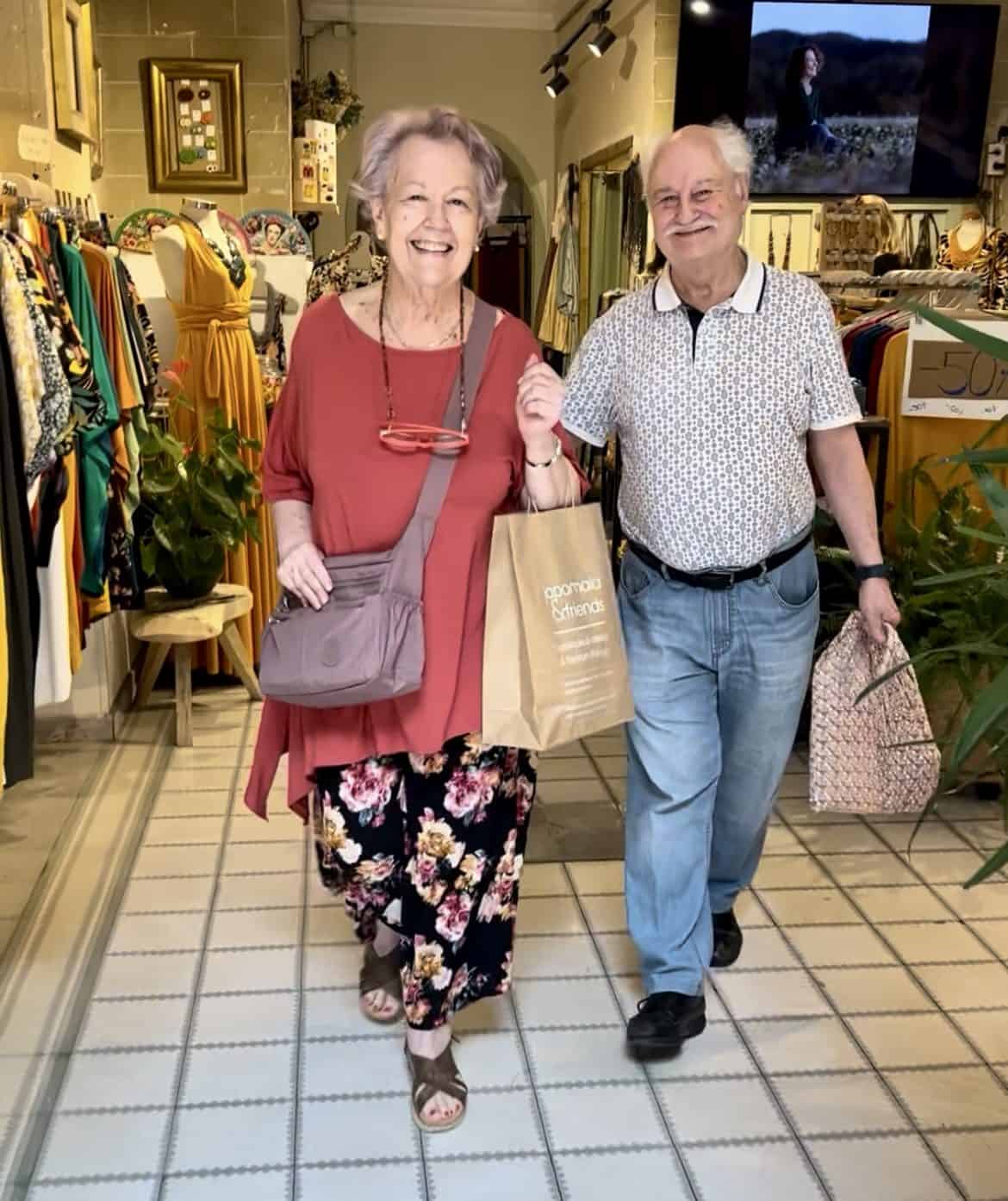 clienta feliz probándo una camisa de verano con estampado colorido hecha en viscosa. Ambiente tranquilo y luz natural de la tienda