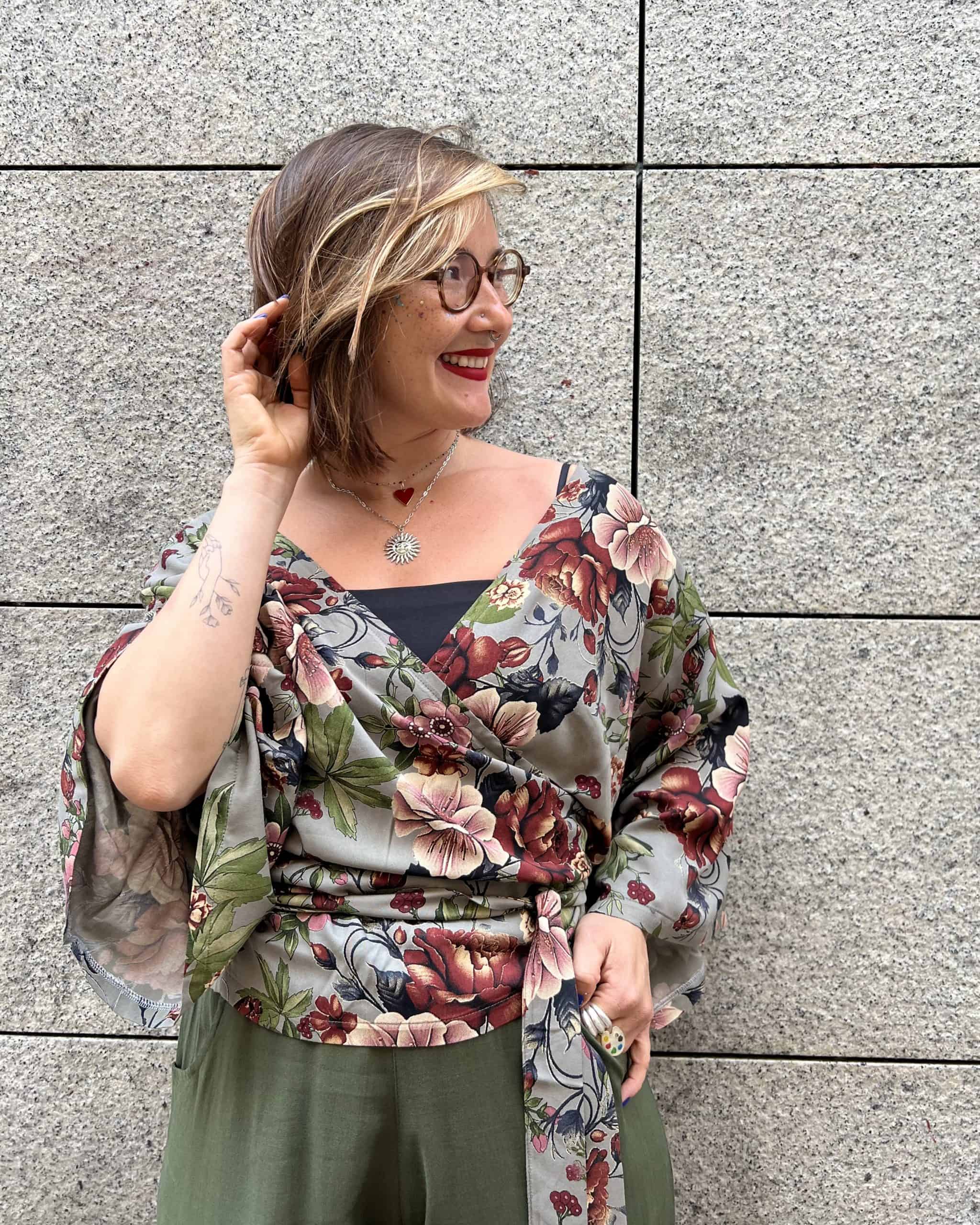 clienta de japamala sonriendo, probándo un top azul en la tienda y un pantalón en un ambiente con luz natural y plantas